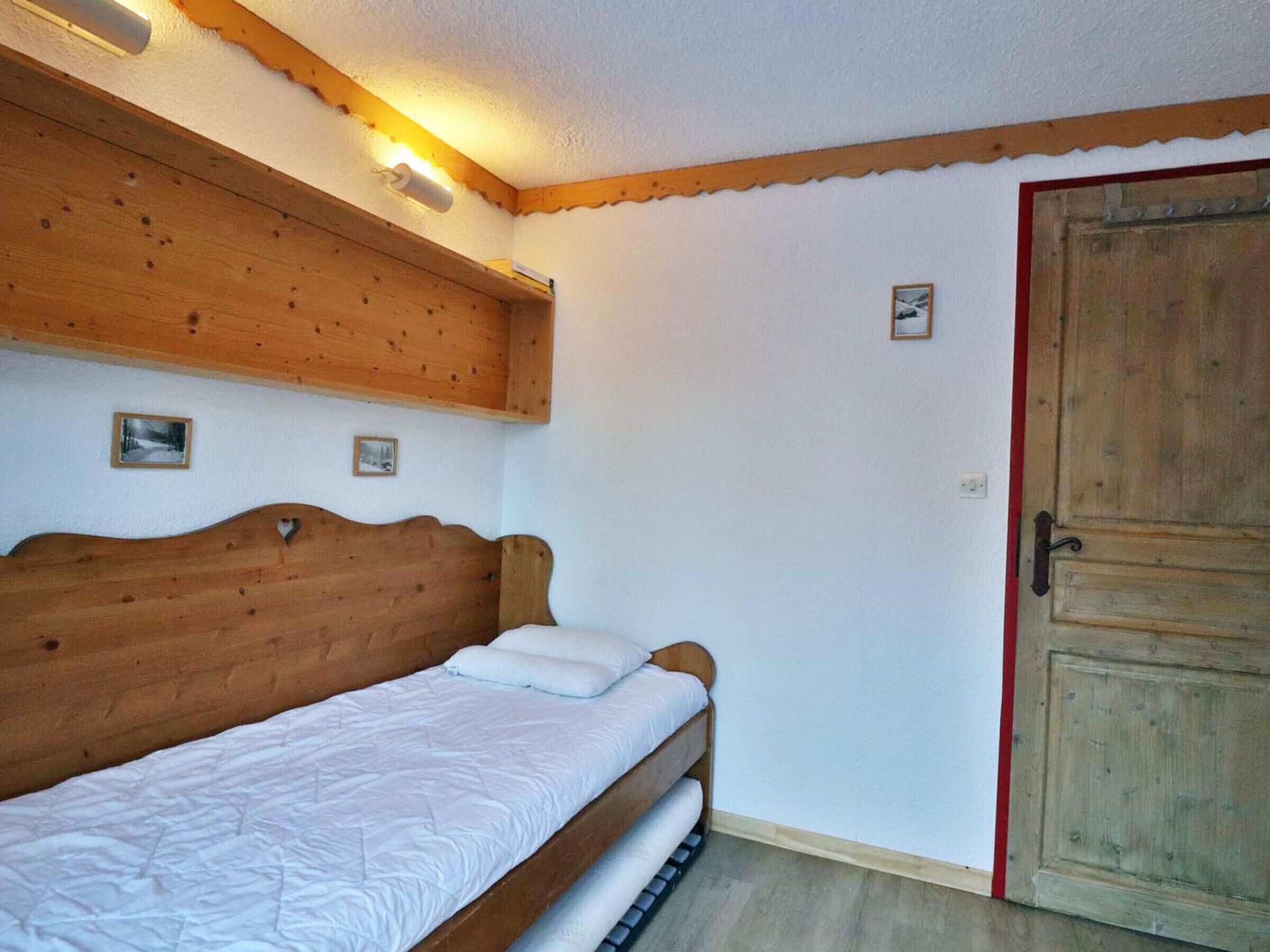 Un lit en bois avec une tête de lit, une porte en bois et un petit tableau accroché au mur.