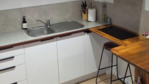 A modern kitchen with a sink, countertop, and a stove. There are three framed pictures on the wall, a white hood above the stove, and a bottle of hand soap on the counter. - Tranquil 1-bedroom apartment with AC in charming Whangārei (Whangārei)