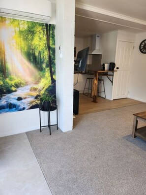 A room with a large forest mural on the wall, a desk with a computer, and a chair.