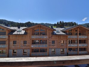 Ein mehrstöckiges Holzgebäude mit Balkonen, vermutlich ein Hotel oder eine Pension, vor einer Bergkulisse.