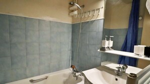 Et badeværelse med badekar, vask og brusebad.