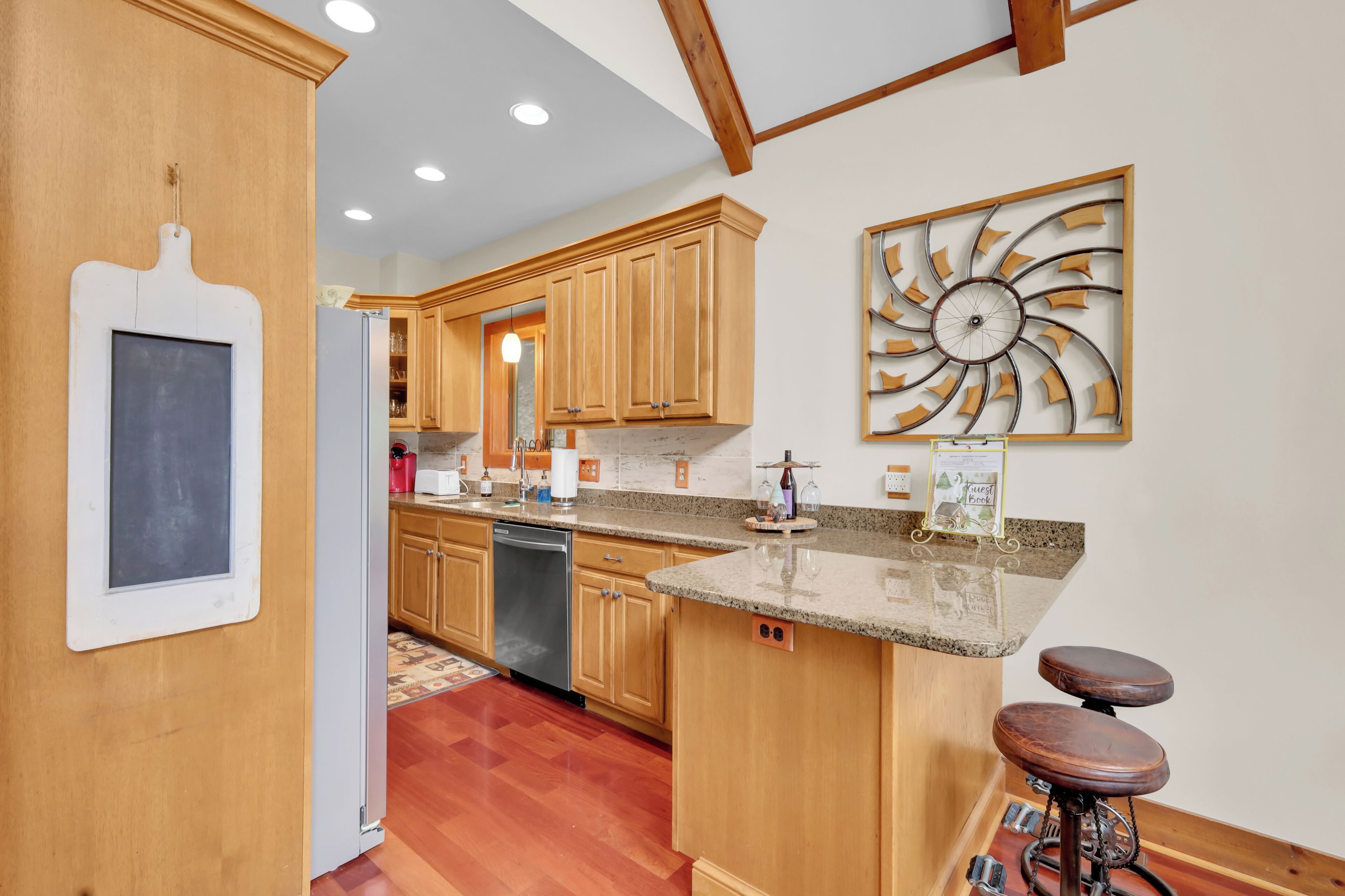 Cocina con armarios de madera, encimera de granito, un taburete para bicicleta y un adorno en la pared.