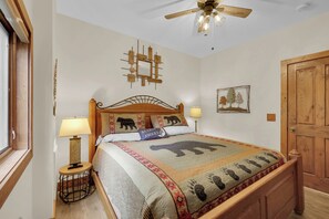 Ein Schlafzimmer mit einem hölzernen Bett, zwei Nachttischlampen, einem Deckenventilator, einer Wandleuchte und einer Tür.