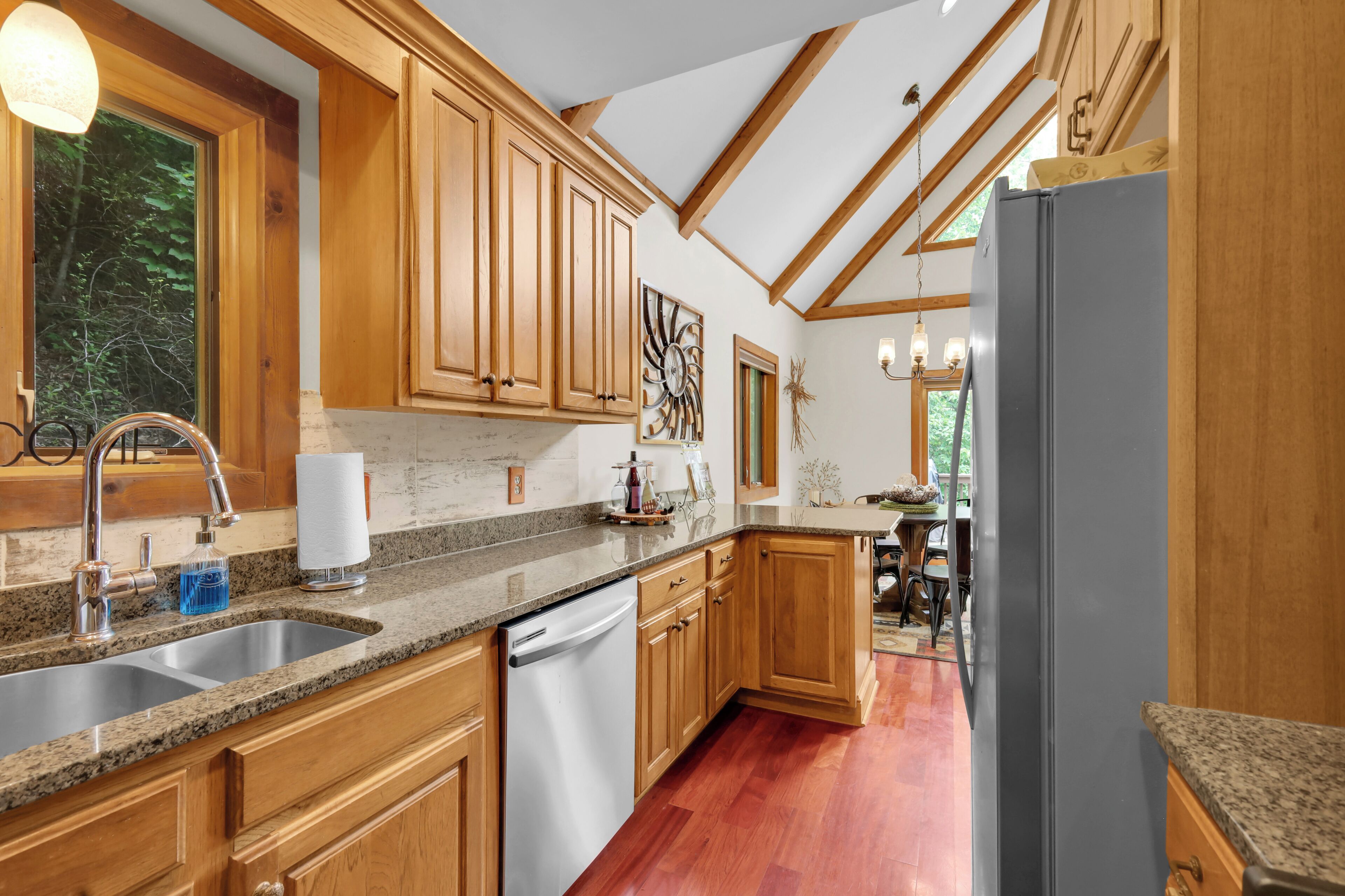 A kitchen with wooden cabinets, granite countertops, a stainless steel sink, and a built-in dishwasher.