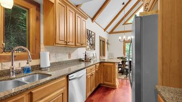 A kitchen with wooden cabinets, granite countertops, a stainless steel sink, and a built-in dishwasher.