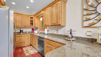 A kitchen with wooden cabinets, granite countertops, a dishwasher, and a decorative wall piece.