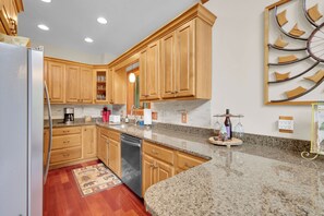 A kitchen with wooden cabinets, granite countertops, a dishwasher, and a decorative wall piece. - Cabin w Views / Hot Tub / Firepit  - close to Boone! (Vilas)