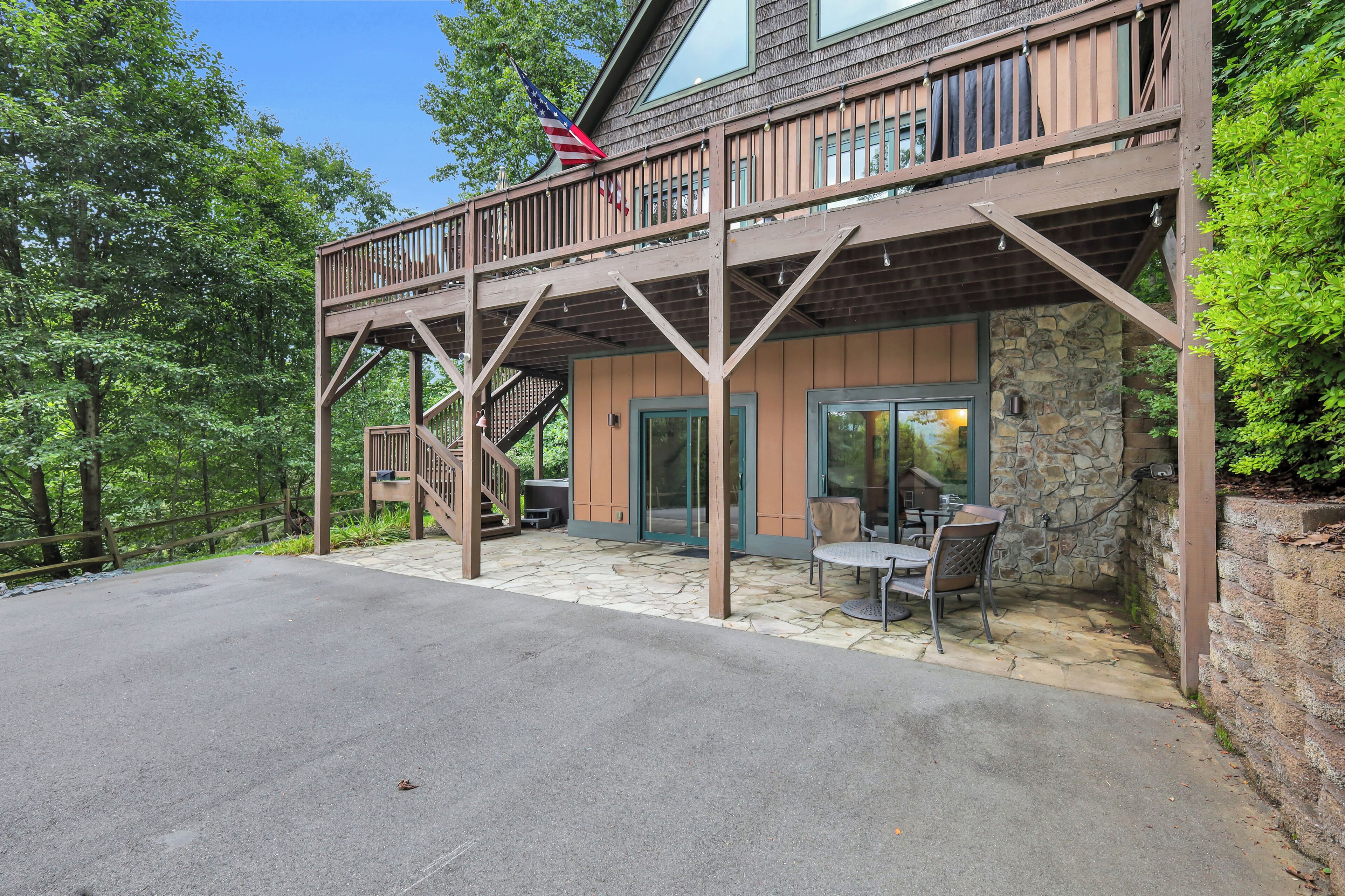 A two-story wooden building with a balcony, stone walls, and a patio area with outdoor seating.