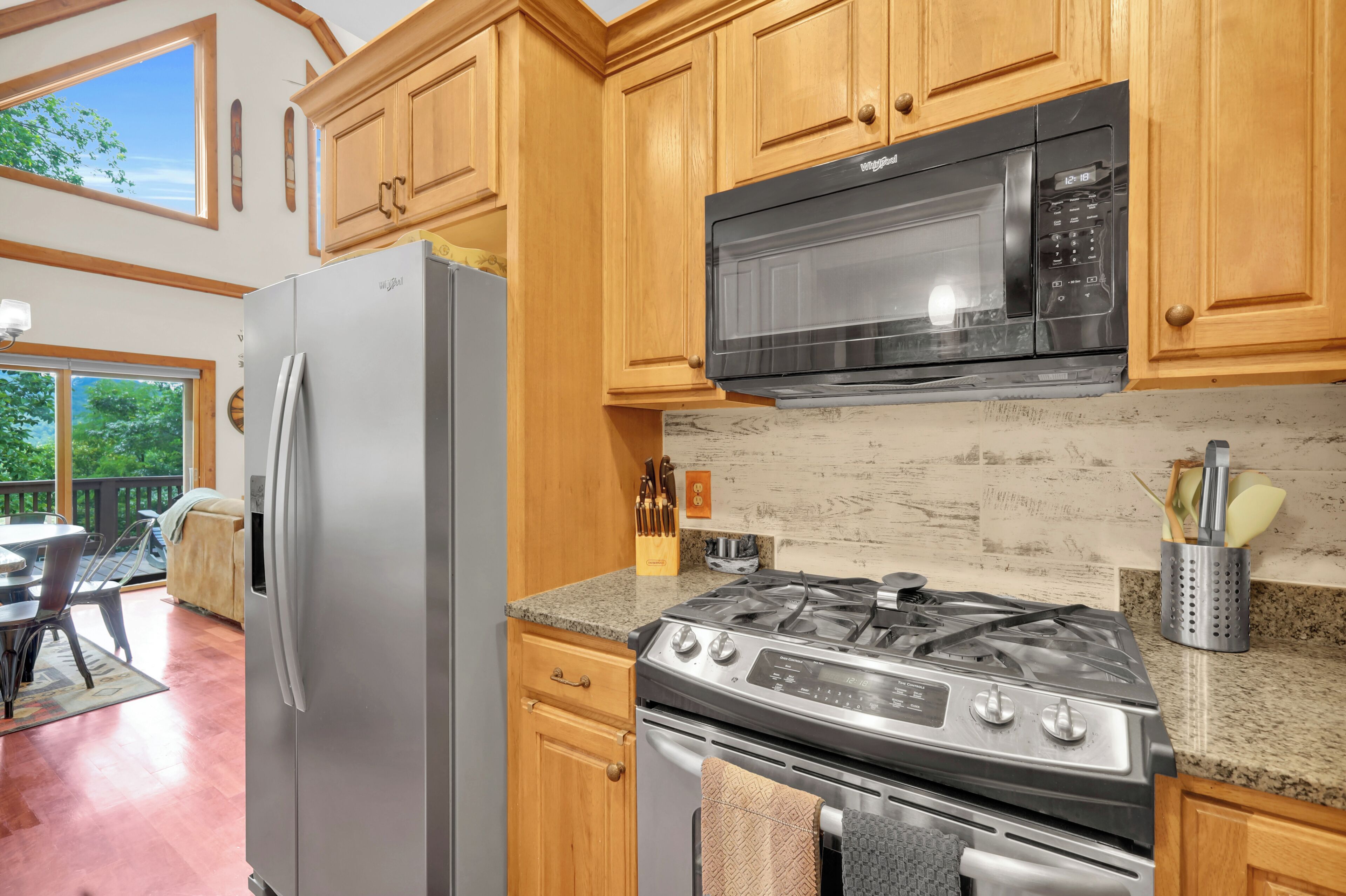 A kitchen with wooden cabinets, a stainless steel refrigerator, a microwave, and a gas stove.