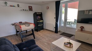 Una sala de estar con una mesa de fútbol de mesa, un juke box Marshall, un televisor y un sofá.