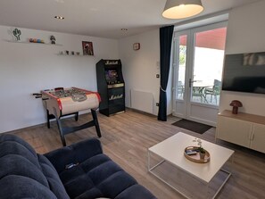 Ein Wohnzimmer mit Kicker, Jukebox von Marshall, Fernseher und einer Couch.