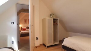 Un dormitorio con una cama, un armario y una puerta que da a otra habitación.