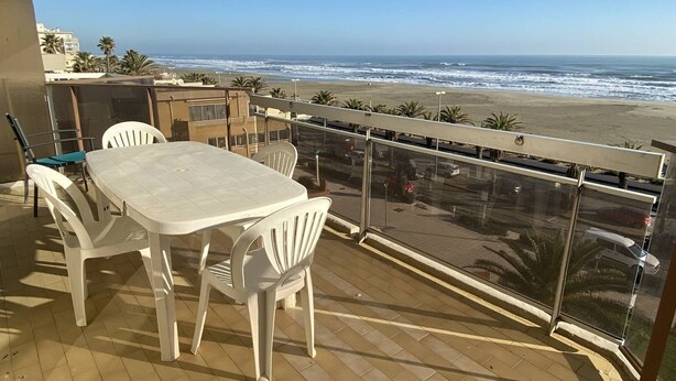 A balcony with a table and chairs, overlooking a beach and ocean. - Apartment with sea view terrace - 4 guests (Canet-Plage)