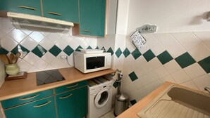 A compact kitchen with teal cabinets, a microwave, a washing machine, and a sink. - Apartment with sea view terrace - 4 guests (Canet-Plage)
