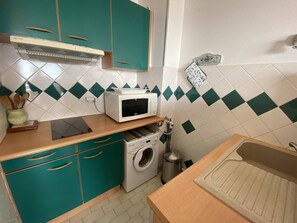 A compact kitchen with teal cabinets, a microwave, a washing machine, and a sink. - Apartment with sea view terrace - 4 guests (Canet-Plage)
