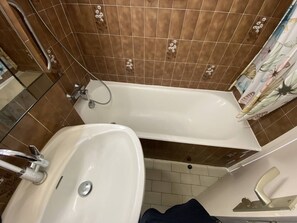 Een badkamer met een bad, een wastafel en een douche.
