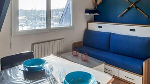 A compact room with a view of a marina, a blue sofa, a table with blue bowls, and a window with a view of the marina.