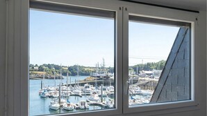 A view through a window of a marina with boats docked, a bridge in the background, and a clear sky.