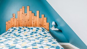 A bedroom with a geometric-patterned bedspread, a wooden headboard, and a bedside table with a lamp.