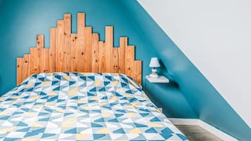 Een slaapkamer met een bedovertrek met een geometrisch patroon, een houten hoofdbord en een nachtkastje met een lamp.