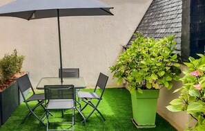 A patio with a table and chairs, a large umbrella, and potted plants. - 2 bedroom gorgeous apartment in Lezardrieux (Lezardrieux)