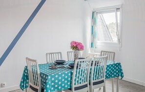 A dining area with a table set for six, white chairs, a teal star-patterned tablecloth, and a vase with pink flowers. - 2 bedroom gorgeous apartment in Lezardrieux (Lezardrieux)