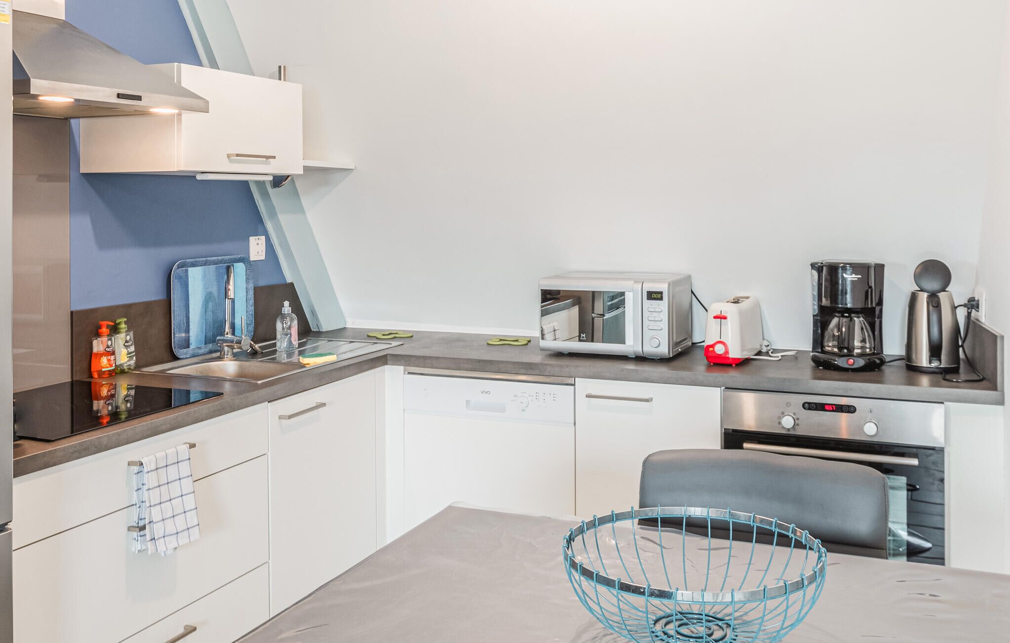 Eine moderne Küche mit Geschirrspüler, Mikrowelle, Toaster und Kaffeemaschine.