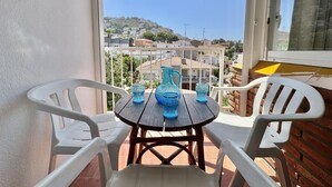 Ein Balkon mit Tisch und Stühlen, der auf einen Wohnbereich mit Häusern und Hügeln blickt.