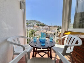 Ein Balkon mit Tisch und Stühlen, der auf einen Wohnbereich mit Häusern und Hügeln blickt.