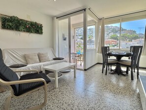 A modern living room with a sofa, a coffee table, and a dining area with chairs and a table. - Apartment with AC and parking - 4 guests (Roses)