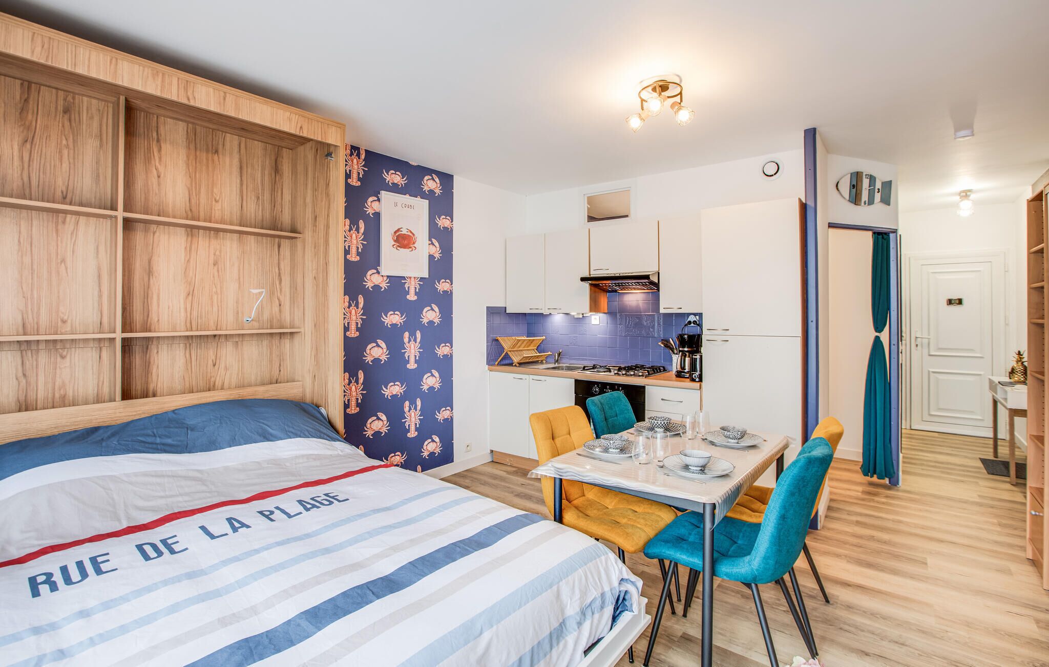 Une chambre avec un lit, une petite table à manger avec des chaises, un coin cuisine et une salle de bain.