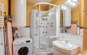 A bathroom with a washing machine, a glass-enclosed shower, a sink, and a mirror. - 1 bedroom lovely apartment in Lezardrieux (Lezardrieux)