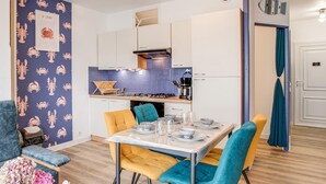 Eine moderne Küche mit weißen Schränken, einer blauen Spritzschutzwand und einem Essbereich mit Tisch für vier Personen.