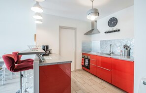 Eine moderne Küche mit roten Schränken, einer Edelstahlspüle und einer Kaffeemaschine.