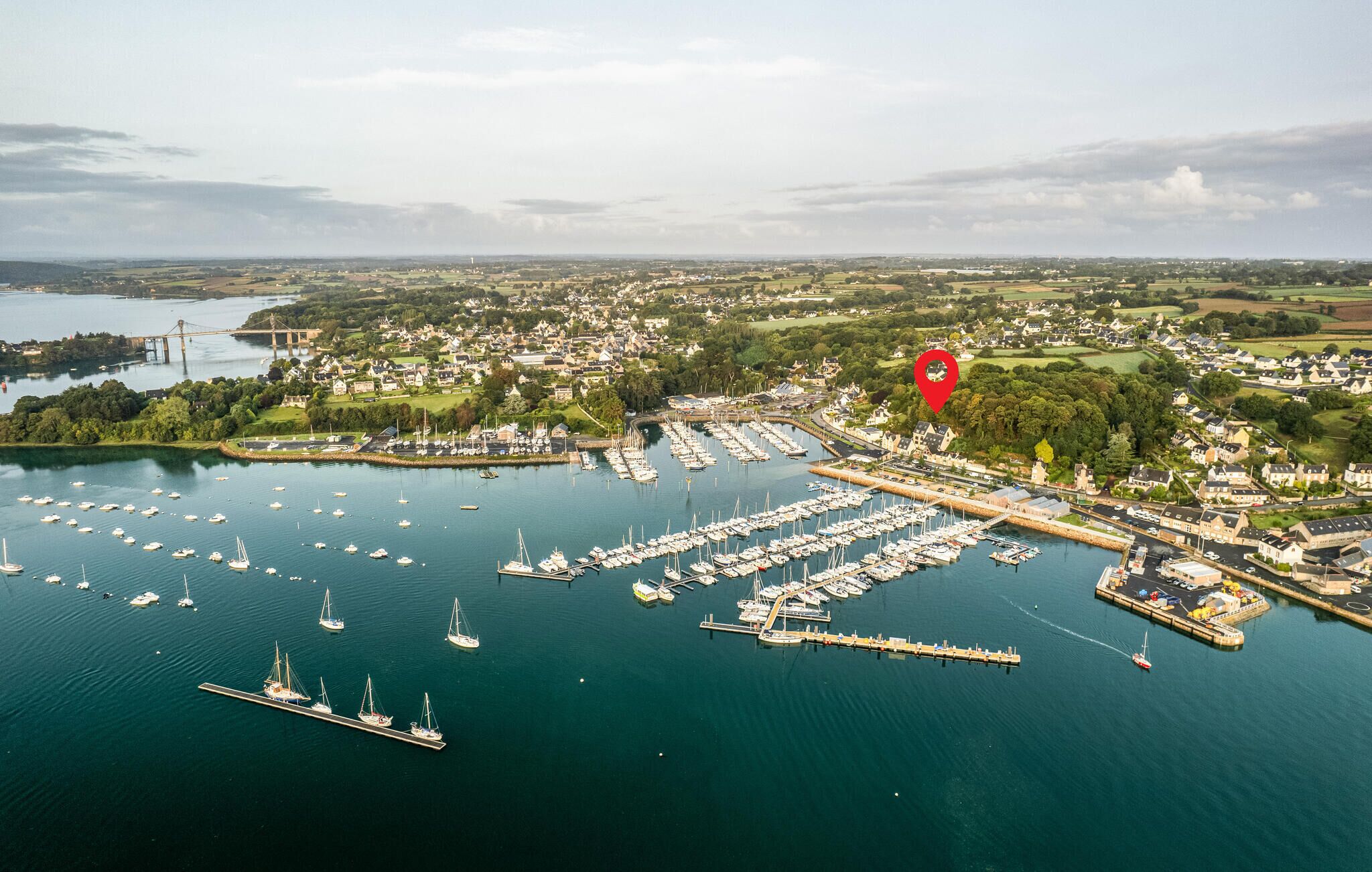 An aerial view of a marina with numerous boats docked, surrounded by residential areas and greenery.