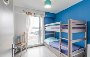 A bunk bed room with a window, a chair, and a ceiling fan. - 2 bedroom amazing apartment in Lezardrieux (Lezardrieux)