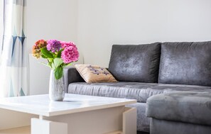 Ein modernes Wohnzimmer mit einem grauen Sofa, einem weißen Couchtisch und einer Vase mit Blumen.