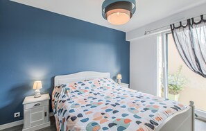 Ein Schlafzimmer mit einem Bett, Nachttischen und einem Fenster mit Vorhängen.