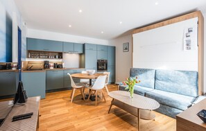 A modern living space with a dining area, a kitchen, and a seating area with a sofa and a coffee table. - Apartment in Lezardrieux (891) (Lezardrieux)