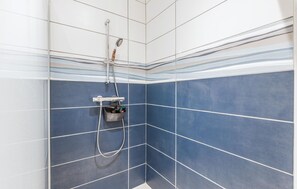 A shower with blue tiles and a handheld showerhead. - Apartment in Lezardrieux (891) (Lezardrieux)