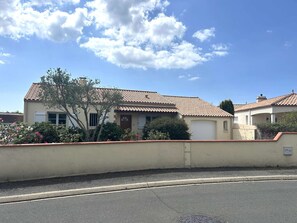 Ein Wohngebäude mit Ziegeldach, Garage und einem gepflegten Garten mit blühenden Pflanzen.