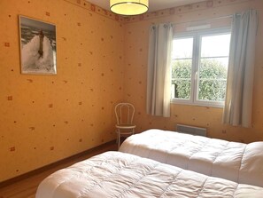A room with two beds, a window with curtains, a chair, and a painting on the wall. - House near the sea - 4 guests (Saint-Hilaire-de-Riez)