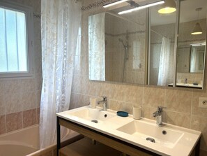 Ein Badezimmer mit einem Doppelwaschbecken, einer Badewanne, einer Dusche und einem großen Spiegel.