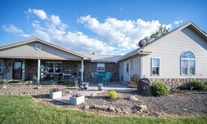 A two-story house with a stone facade, a covered porch, and a patio with outdoor furniture. - Quiet Amish Country Getaway | Fire Pit & Grill (Millersburg)