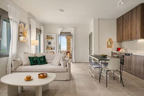 A modern living room with a sofa, a dining table, and a kitchen area with wooden cabinets. - Apartment 'Aliki' with Sea and Taygetos Mountain View (West Mani)