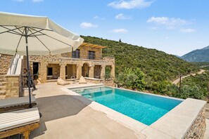 A stone building with a pool, outdoor seating, and a view of a hilly landscape. - Apartment 'Aliki' with Sea and Taygetos Mountain View (West Mani)