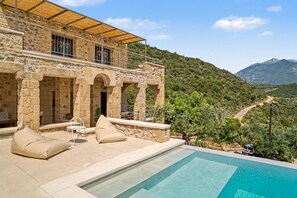 Ein Steinhaus mit Pool, Sitzgelegenheiten im Freien und Blick auf eine gebirgige Landschaft.