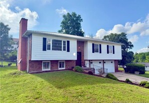 A two-story house with a brick facade, white siding, and a front porch. - Charming 3 bedroom house in St Robert. Only 3 minutes from the main gate of FLW. (Saint Robert)