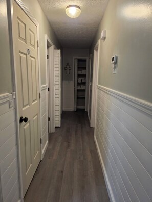 A hallway with white doors, a cross decoration, and a thermostat on the wall. - Charming 3 bedroom house in St Robert. Only 3 minutes from the main gate of FLW. (Saint Robert)