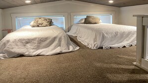 A bedroom with two beds, wooden ceiling, and a ceiling-mounted security camera. - Sunrise Cottage at River Rocks Landing (Gadsden)